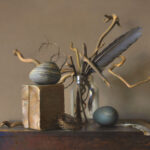 A still life by a Duluth MN artist features a jar with twisted branches and a large feather, a wooden block with a striped round object on top, a small empty nest, and a smooth dark sphere placed on a rustic table.