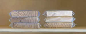 Six stacks of packaged golden crackers, reminiscent of a Duluth MN artist's palette, are neatly arranged in rows of three on a shelf, set against a plain neutral background. The packaging is slightly glossy, reflecting light softly.