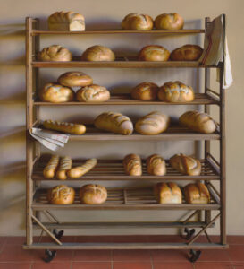 A wooden bakery rack, reminiscent of a Duluth MN artist's creation, showcases freshly baked bread—round loaves, baguettes, and rolls—across five shelves. A folded cloth graces the upper right shelf as the rack stands elegantly on a tiled floor against a plain wall.