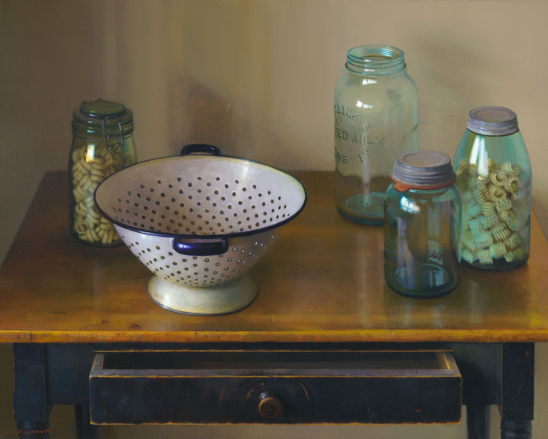 A vintage colander sits on a wooden table, surrounded by glass jars filled with pasta. One jar is open, and the table's drawer is slightly ajar. The scene, reminiscent of a Duluth MN Artist's touch, exudes a warm, rustic feel with soft lighting.