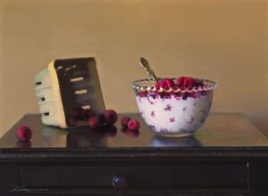 A still life painting by a Duluth MN artist features a wooden table adorned with a decorative bowl brimming with raspberries and a silver spoon. Nearby, an empty wooden basket rests, with scattered raspberries beside it against the backdrop of a plain beige wall.