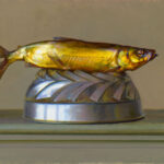 A realistic painting by a Duluth MN artist depicts a golden fish lying horizontally on a silver, spiral-patterned base. The background is a muted, pale color, emphasizing the fish's vibrant hues.