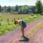 A Duluth MN artist in a gray dress bends down on a sunlit dirt road surrounded by lush green fields and trees. The scene is peaceful, with a clear blue sky framing the tranquil landscape.