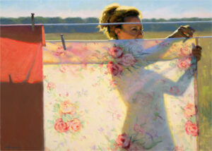 A Duluth MN artist hangs floral-patterned sheets on an outdoor clothesline. The scene is brightly lit by the sun, casting shadows on the fabric. In the background, a blurred landscape of fields unfurls under a clear sky.