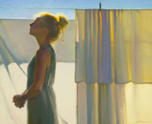 A woman with her hair in a bun stands in profile with eyes closed, perhaps reflecting or savoring the sunlight. Behind her, light yellow and white sheets hang on a line, casting soft shadows in the bright light—a serene scene captured by a talented Duluth MN artist.