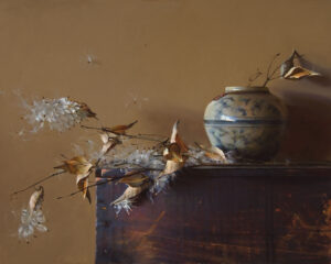 A Duluth MN artist captures a still life painting with a ceramic vase adorned with a blue pattern on a wooden surface. The vase cradles delicate, feathery white flowers and dried leaves, set against a warm, muted background, while seeds float gently in the air.