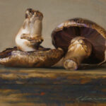 A still life painting by a Duluth MN artist depicts two mushrooms resting on a textured surface. One mushroom stands upright, while the other tilts to reveal its gills. The artwork features warm, earthy tones and a subtle play of light and shadow.