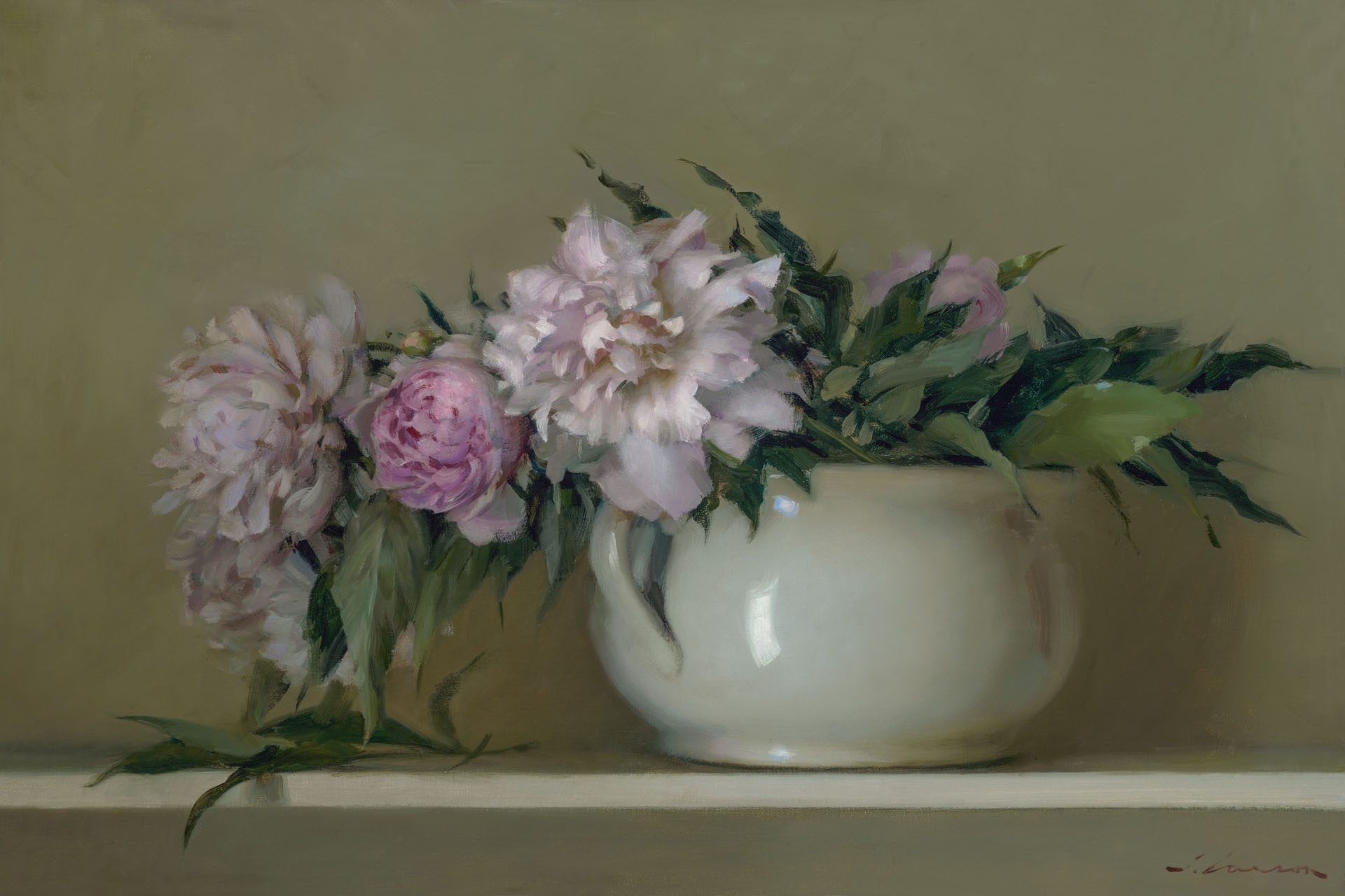 A white ceramic vase, crafted by a Duluth MN artist, holds a bouquet of pink and white peonies with leafy green stems, set against a muted olive-green backdrop. One peony lies gracefully beside the vase on a light-colored surface.