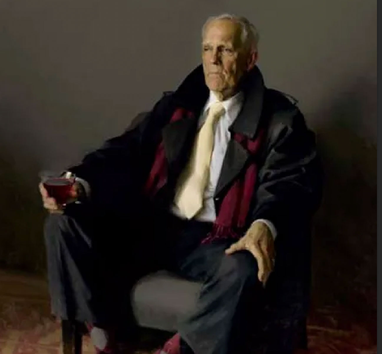 An older man wearing a dark coat and a white tie sits in an armchair holding a glass of red drink, looking serious in a dimly lit setting.
